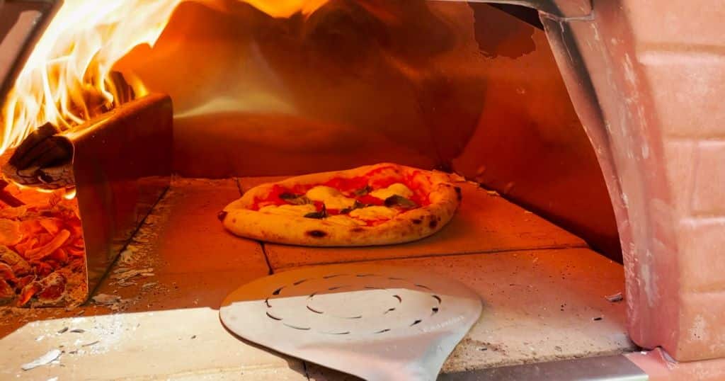 Pizza Party 70x70 Review: An Old-School Wood Burning Monster Pizza Oven Neapolitan pizza baking next to a roaring wood fire.