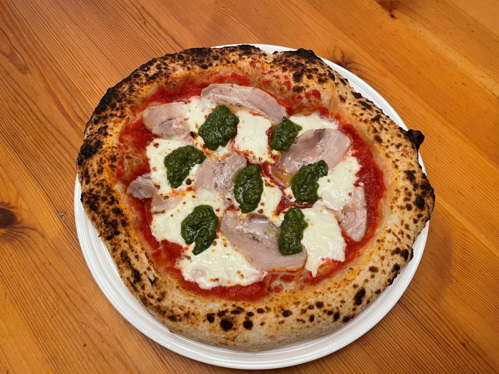 Neapolitan-style pizza with cheese, pork belly, and basil pesto.